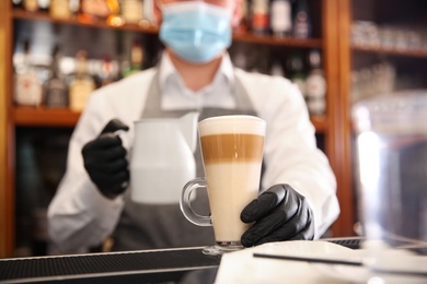 Photo of Barista preparing coffee at counter in restaurant, closeup. Catering during coronavirus quarantine