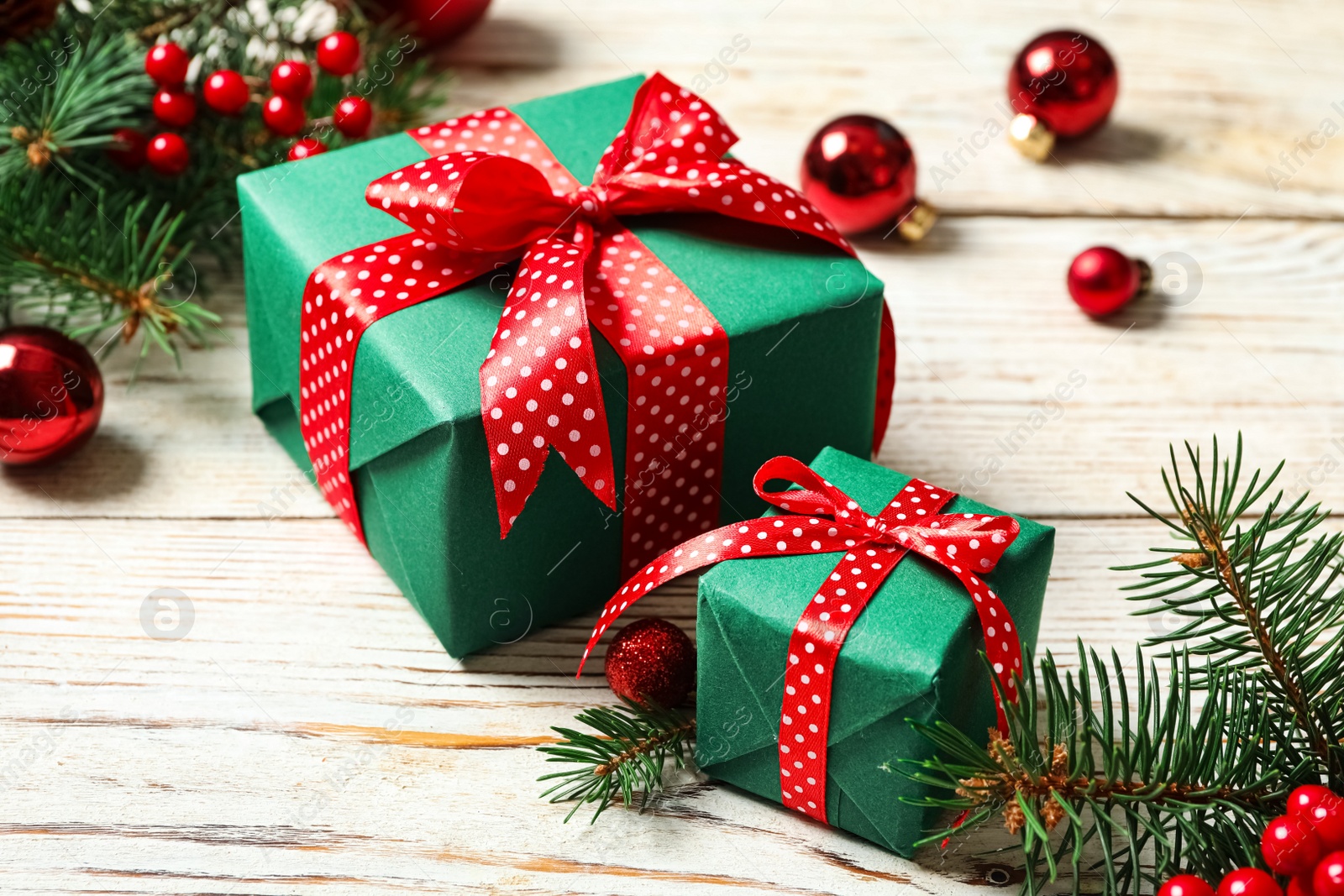 Photo of Gift boxes, fir branches and Christmas balls on white wooden table