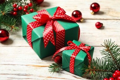 Photo of Gift boxes, fir branches and Christmas balls on white wooden table