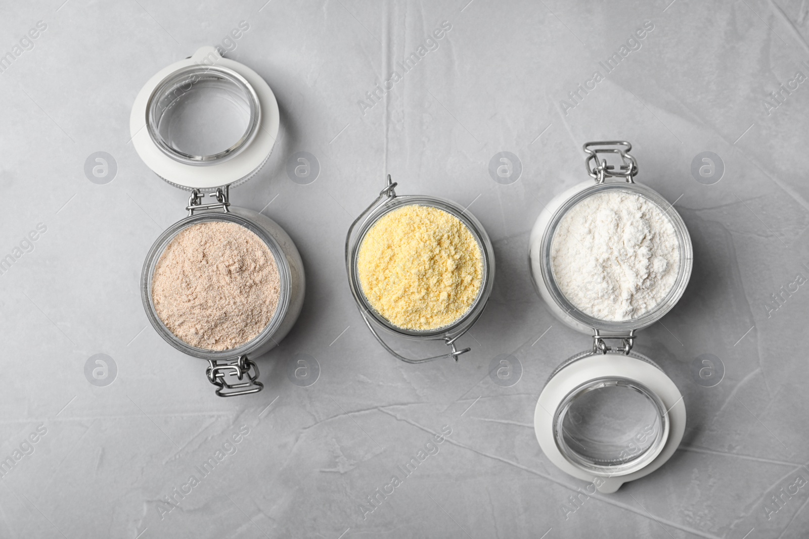 Photo of Jars with different types of flour on gray background