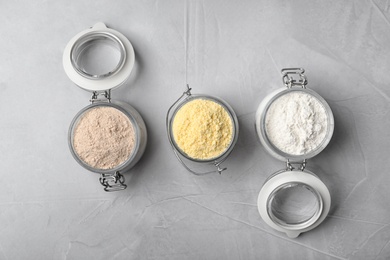 Photo of Jars with different types of flour on gray background