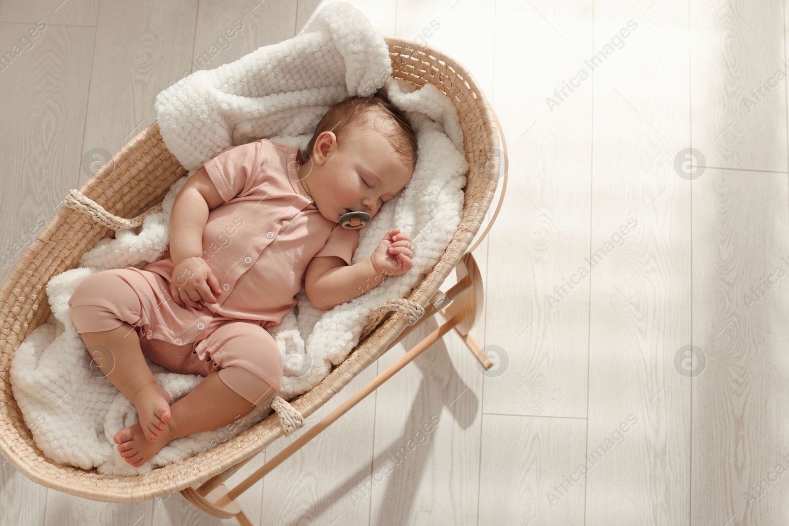 Photo of Cute little baby with pacifier sleeping in wicker crib at home, top view. Space for text