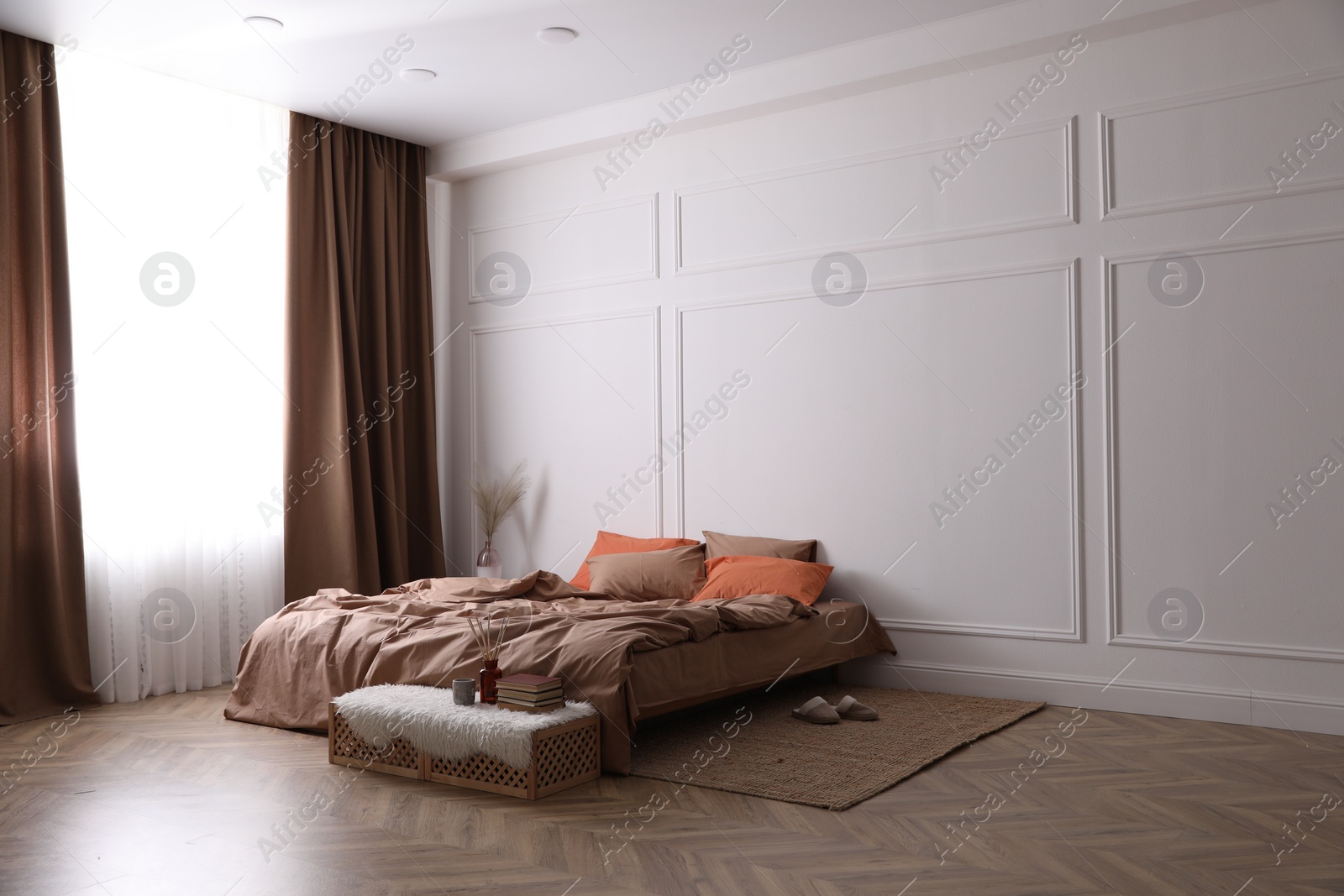 Photo of Bed with orange and brown linens in stylish room