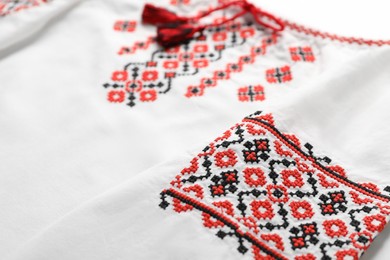 Photo of Beautiful white shirt with red Ukrainian national embroidery, closeup. Space for text