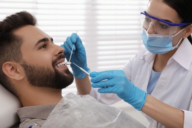 Photo of Dentist examining young man's teeth in modern clinic