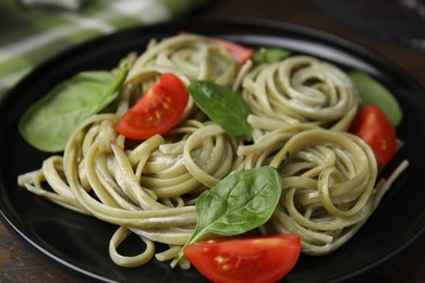 Photo of Tasty pasta with spinach, sauce and tomatoes on table, closeup