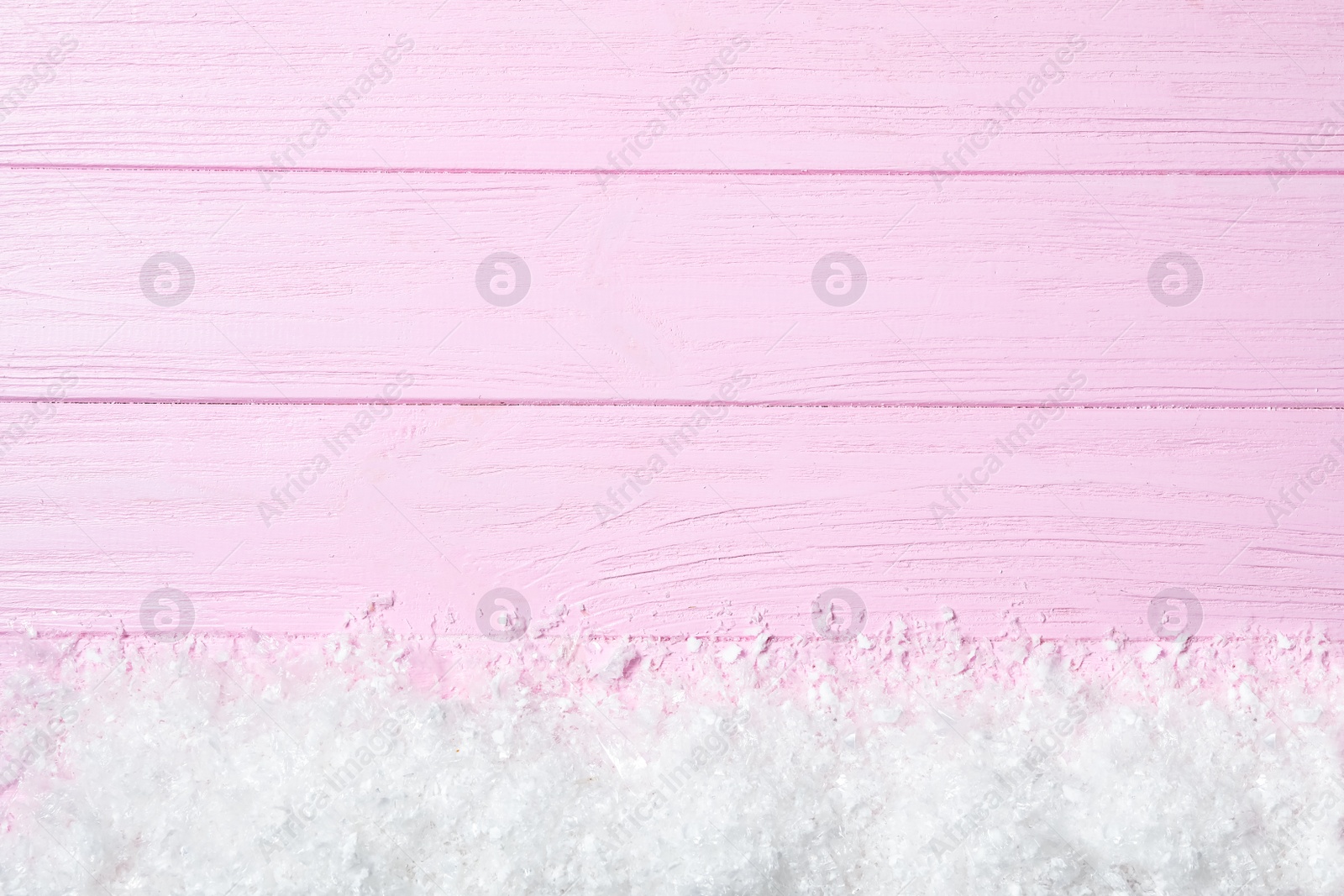 Photo of Heap of snow and space for text on pink wooden background, top view. Christmas time