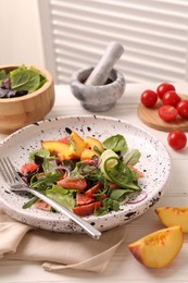 Photo of Delicious salad with vegetables and peach served on white wooden table