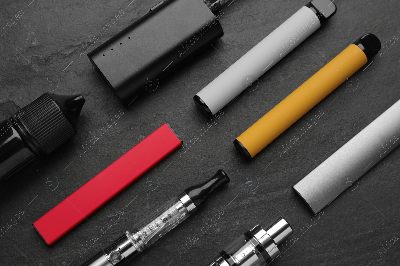 Photo of Many electronic smoking devices on black background, flat lay