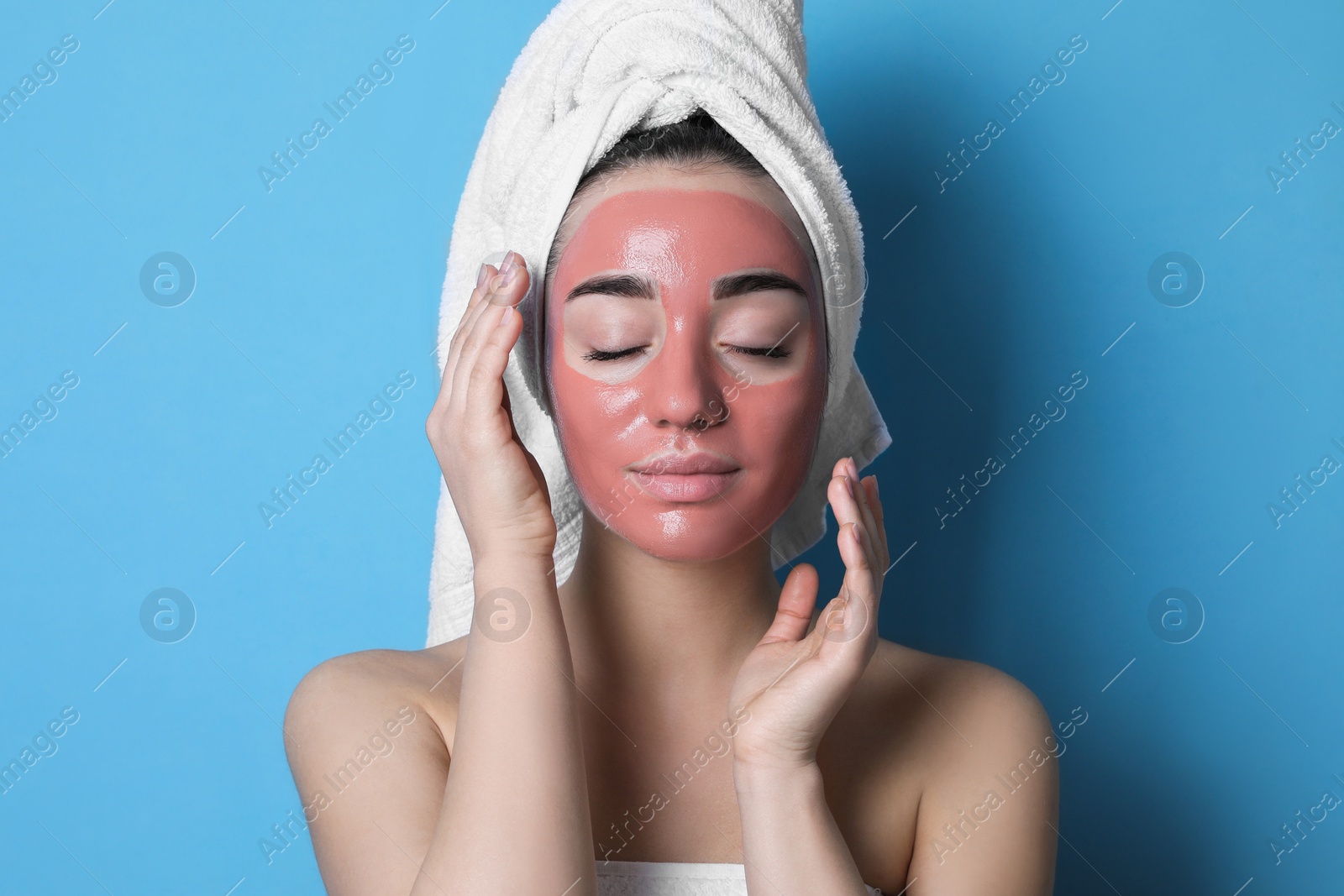 Photo of Woman with pomegranate face mask on light blue background