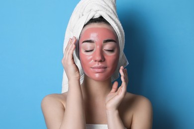 Woman with pomegranate face mask on light blue background