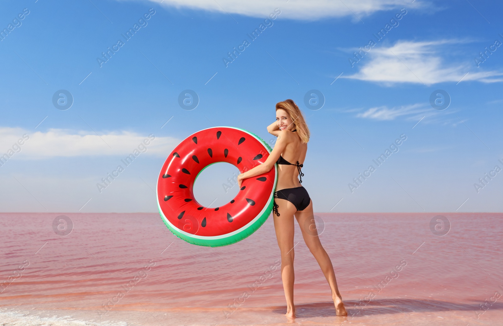 Photo of Beautiful woman with inflatable ring posing near pink lake on sunny day