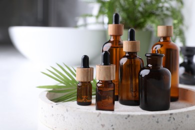 Tray with bottles of essential oils on white table in bathroom, closeup. Space for text