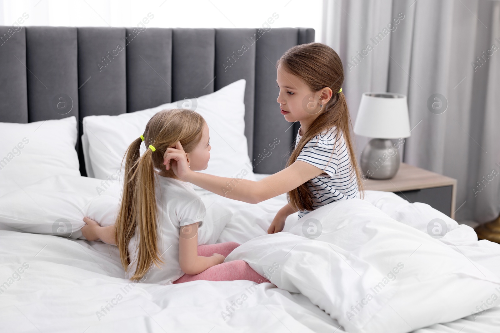 Photo of Cute little sisters on bed at home