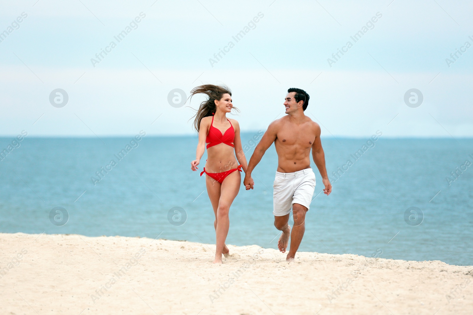 Photo of Happy young couple running together on sea beach