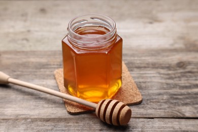 Photo of Sweet honey in jar and dipper on wooden table