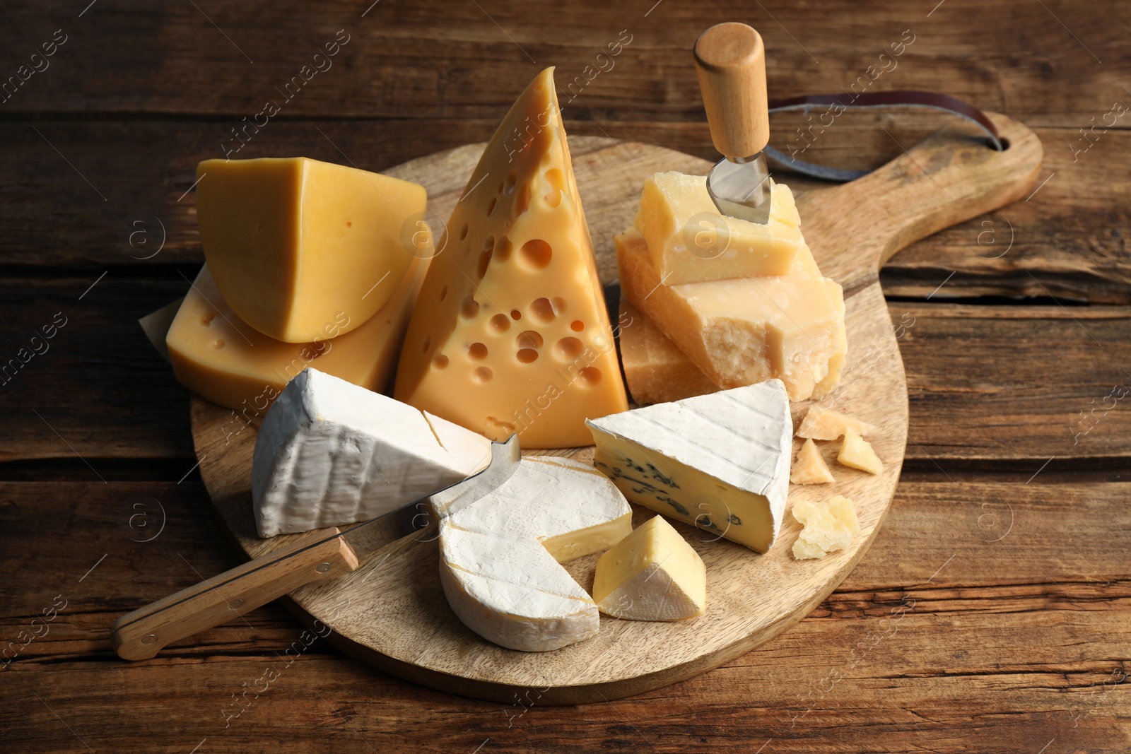 Photo of Different sorts of cheese and knives on wooden table