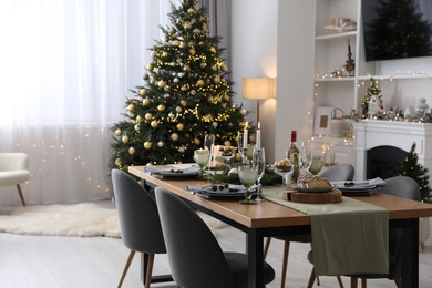 Photo of Christmas table setting with festive decor and dishware in living room interior