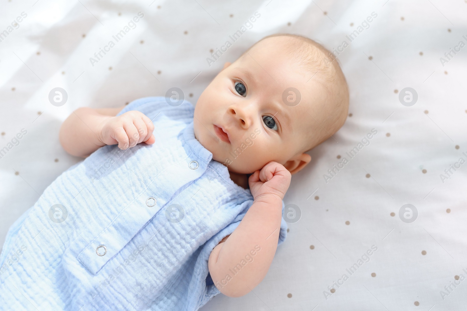 Photo of Cute little baby lying in crib at home, top view