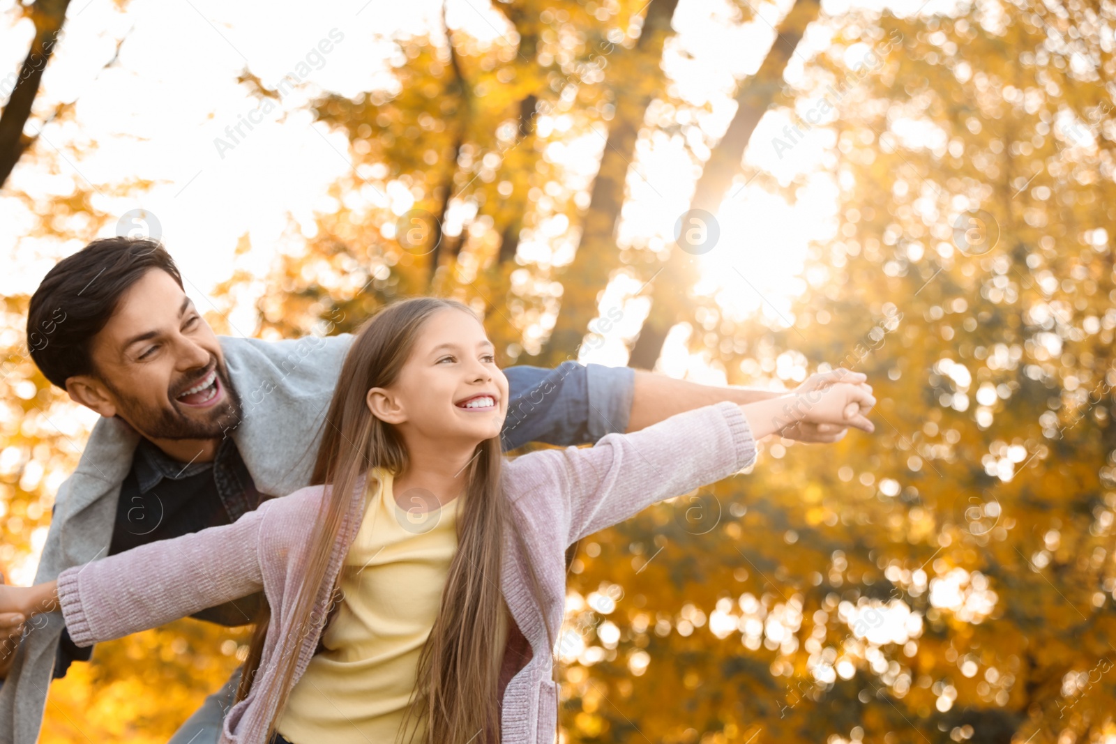 Photo of Happy father with daughter in sunny park. Autumn walk