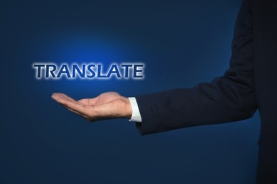 Image of Man showing virtual model of word TRANSLATE against dark blue background, closeup