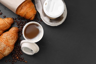 Photo of Coffee to go. Paper cups of tasty drink, croissants and beans on black table, flat lay with space for text