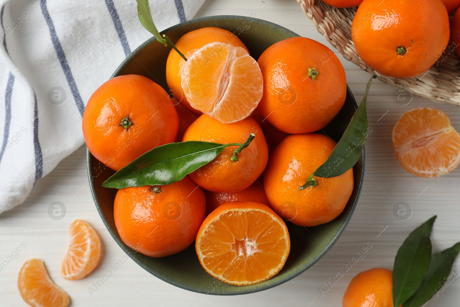 Photo of Delicious tangerines with green leaves on white wooden table, flat lay