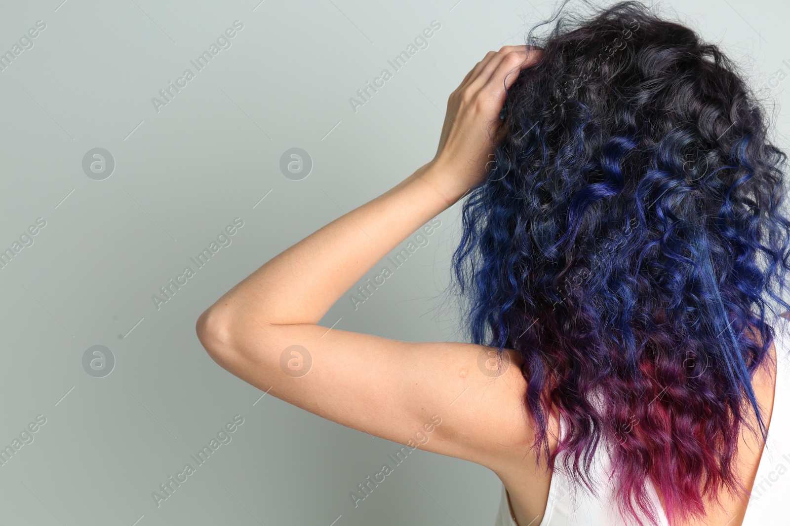 Photo of Young woman with bright dyed hair on grey background, back view