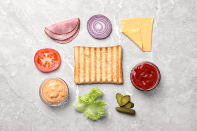 Fresh ingredients for tasty sandwich on light grey background, flat lay