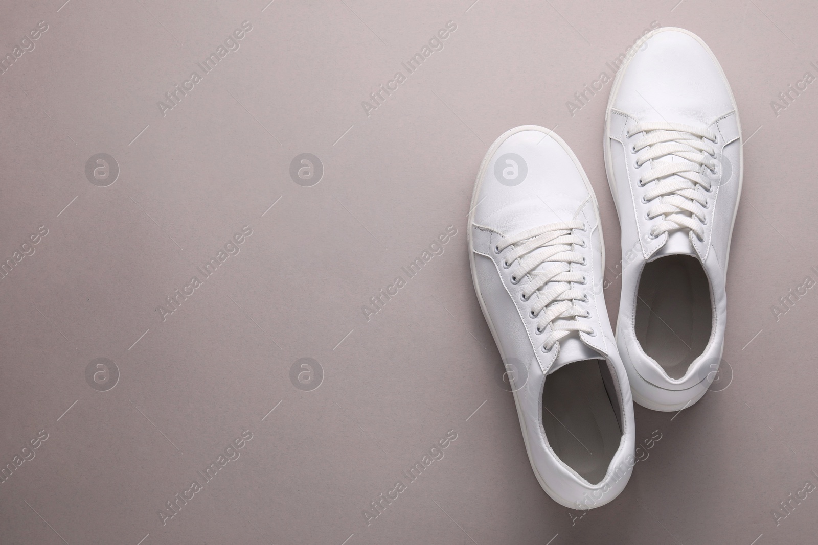 Photo of Pair of stylish white sneakers on grey background, top view. Space for text