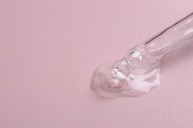 Pipette with cosmetic serum on pink background, space for text