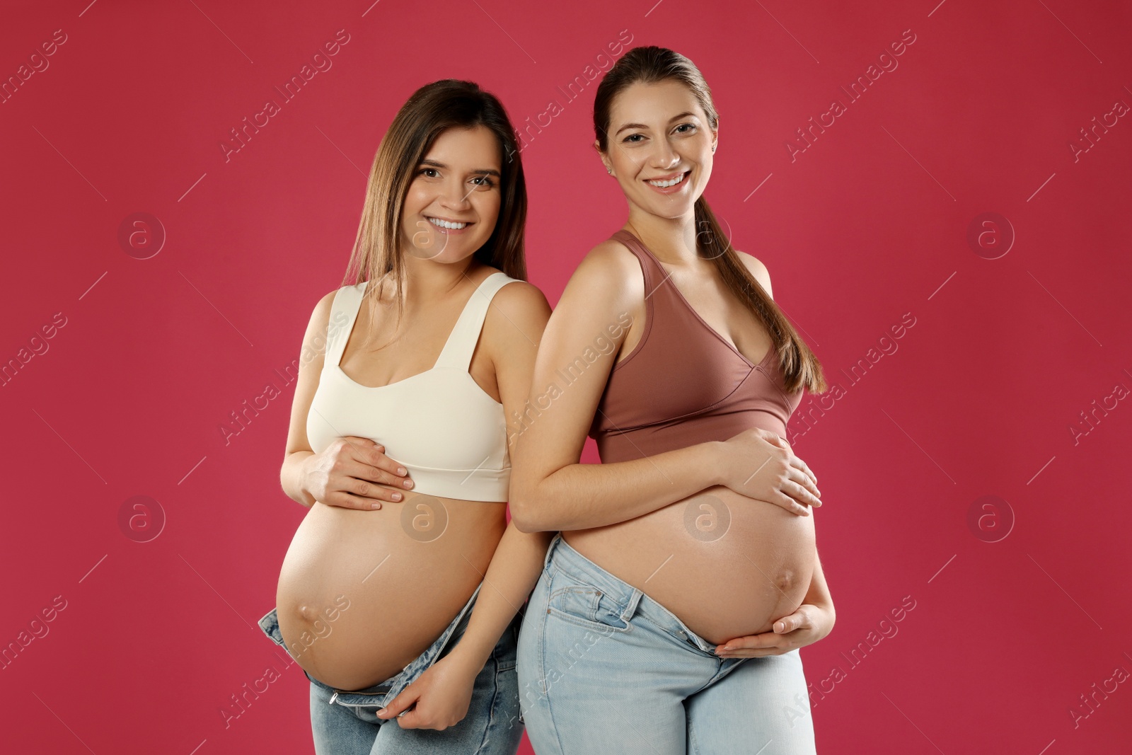 Photo of Happy young pregnant women on red background