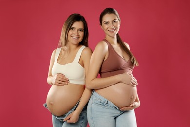 Photo of Happy young pregnant women on red background