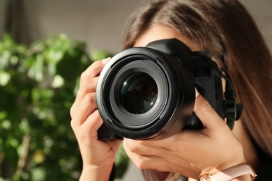 Photo of Female photographer with professional camera on blurred background, closeup