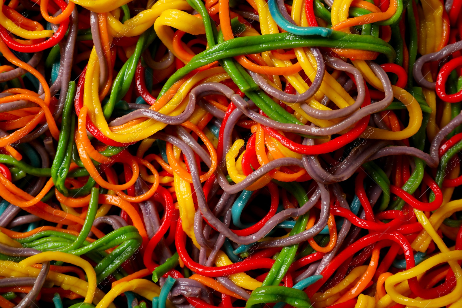 Photo of Spaghetti painted with different food colorings as background, top view