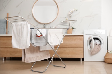 Clean laundry hanging on drying rack in bathroom. Space for text