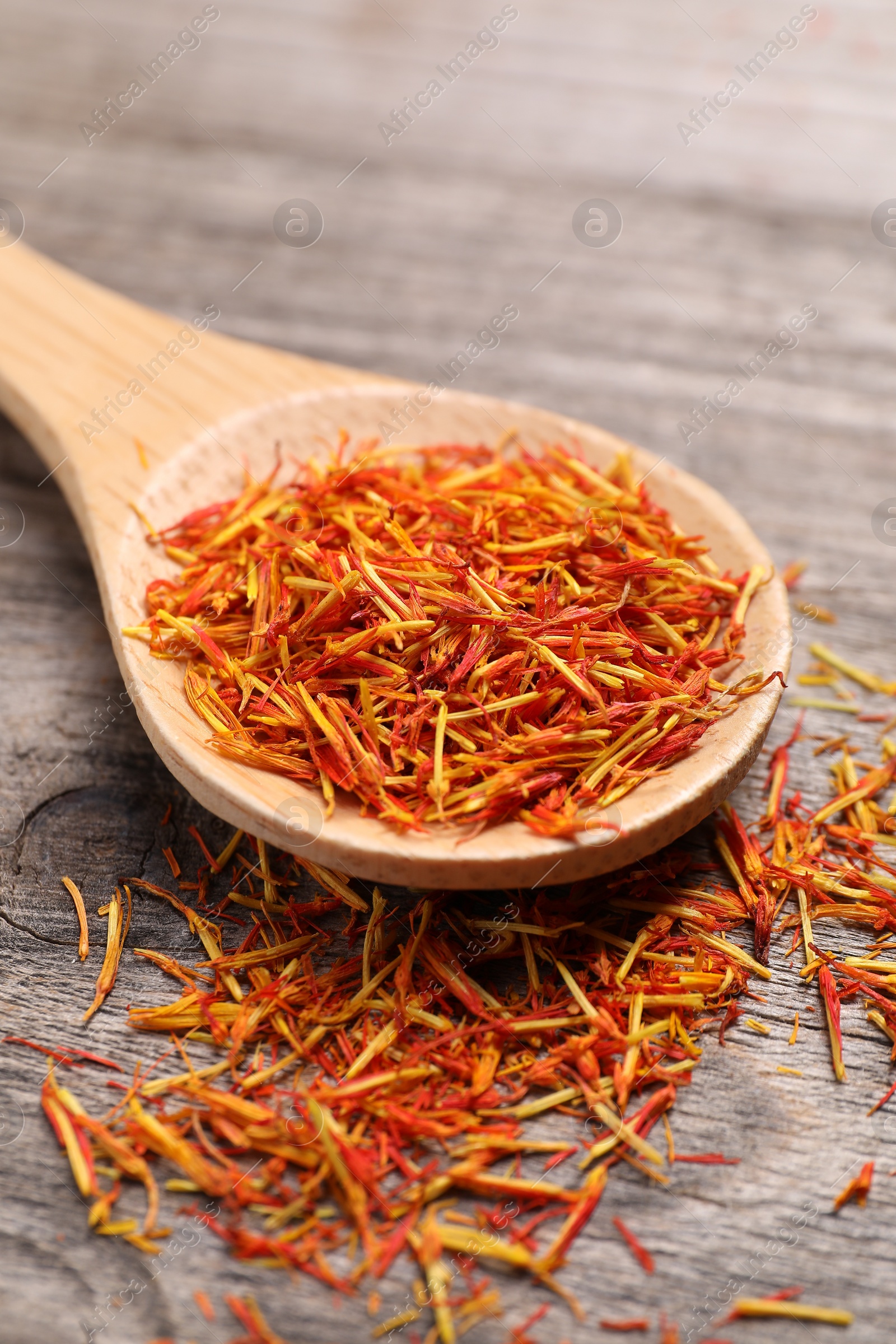 Photo of Aromatic saffron and spoon on wooden table, closeup