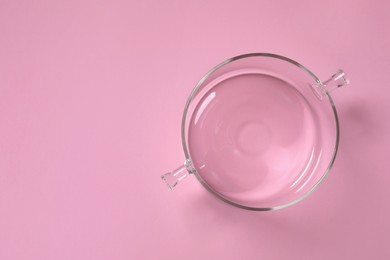 Empty glass pot on pink background, top view. Space for text