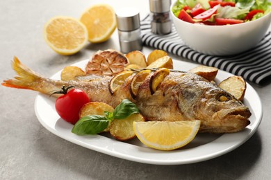 Photo of Tasty homemade roasted perch with garnish on grey table. River fish