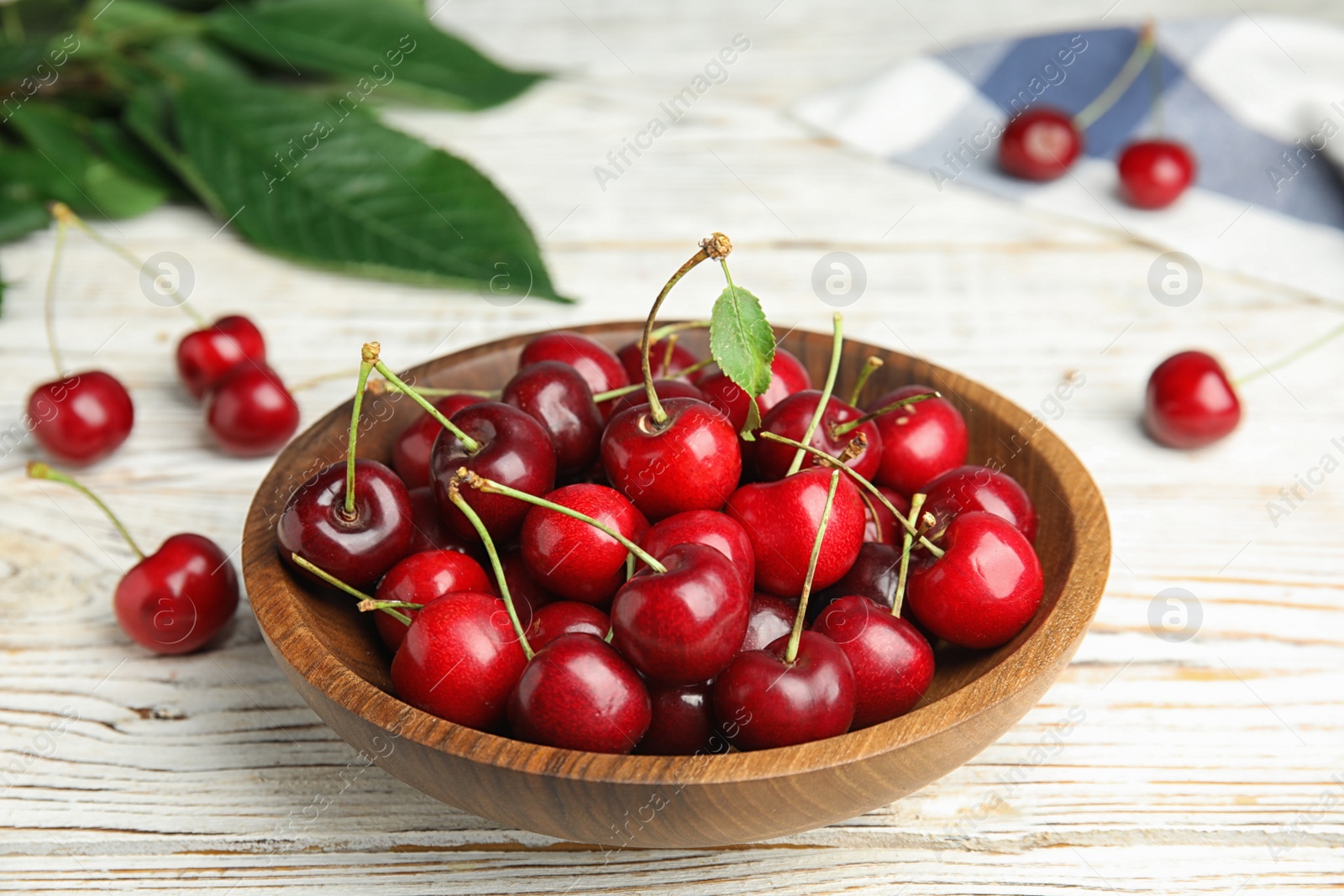 Photo of Bowl with ripe sweet cherries on white wooden table