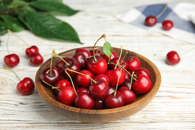 Photo of Bowl with ripe sweet cherries on white wooden table