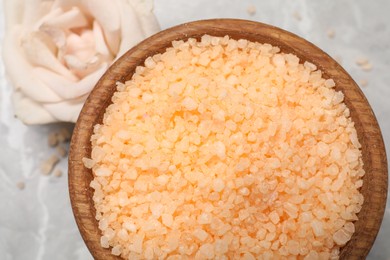 Photo of Orange sea salt in bowl and rose on grey table, top view