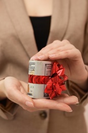 Woman holding bundle of dollars tied with ribbon, closeup