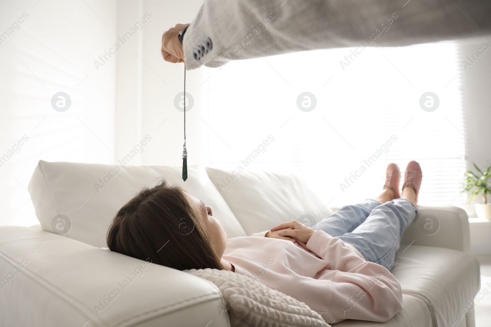 Photo of Psychotherapist using pendulum during hypnotherapy   session in office