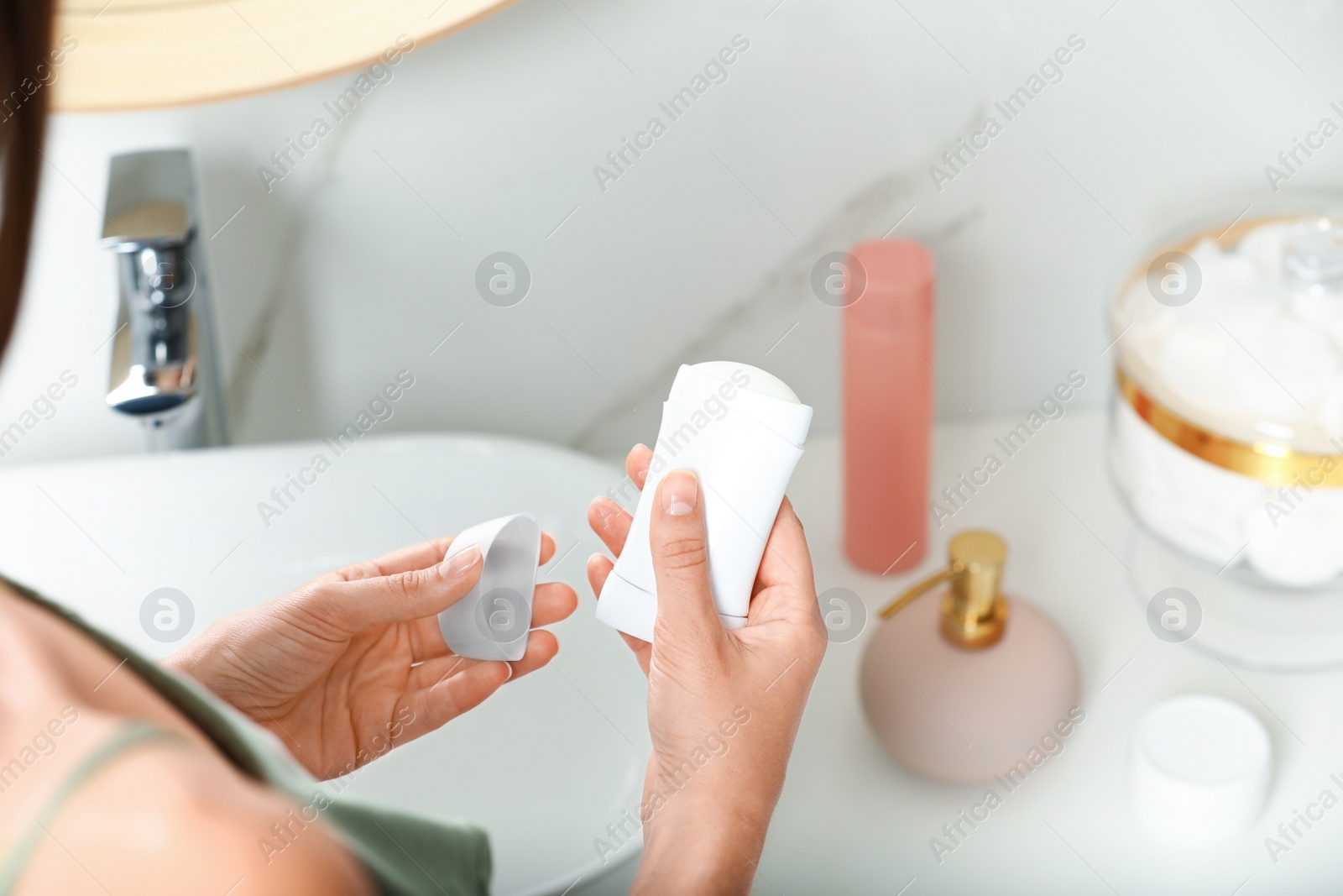 Photo of Woman holding stick deodorant in bathroom, closeup view