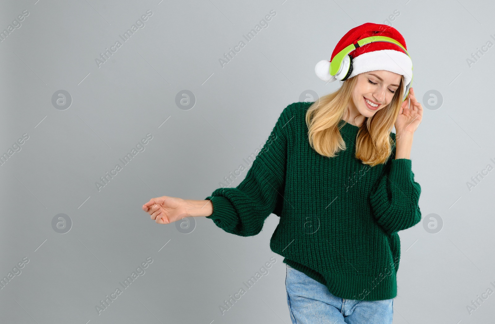 Photo of Happy woman with headphones on grey background, space for text. Christmas music