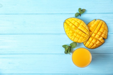 Glass with fresh mango juice and tasty fruits on wooden table, flat lay. Space for text