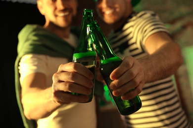 Photo of Men with beer celebrating St Patrick's day in pub, focus on hands