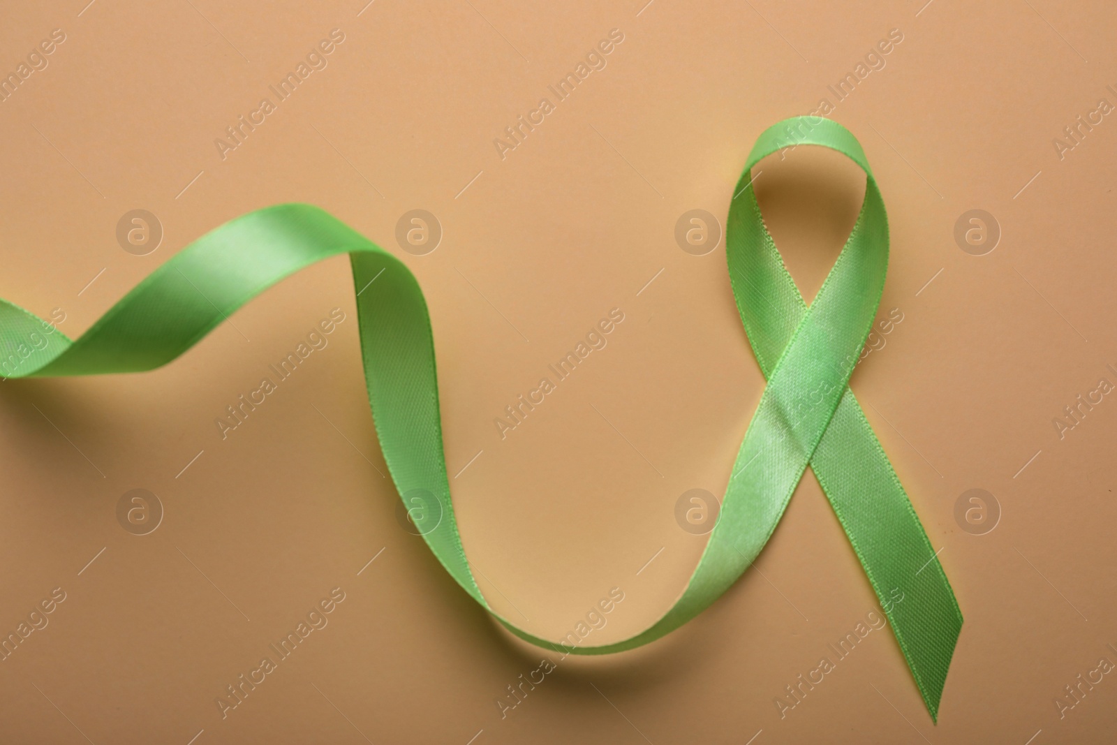 Photo of World Mental Health Day. Green ribbon on color background, top view