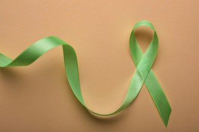 World Mental Health Day. Green ribbon on color background, top view